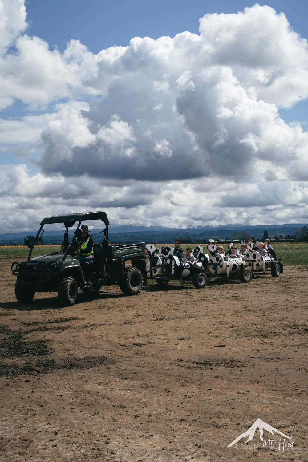 Kids riding in cow themed pods behind a tractor